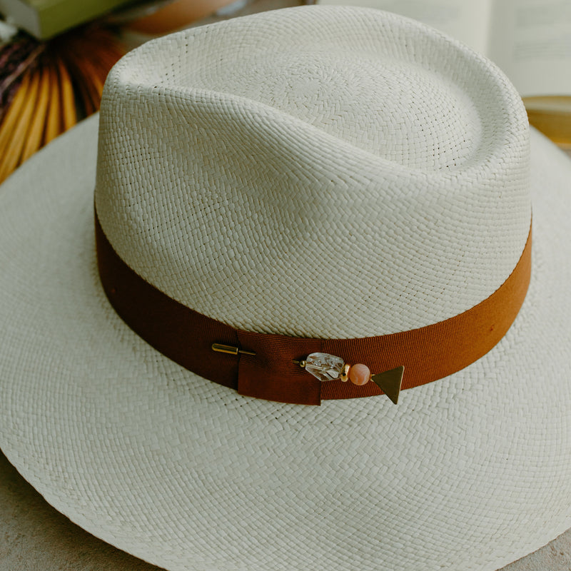 The Isla Rae Beach Hat from Sol Authentica, offering sun protection with a stylish exaggerated brim and a handcrafted bronze gemstone pin.